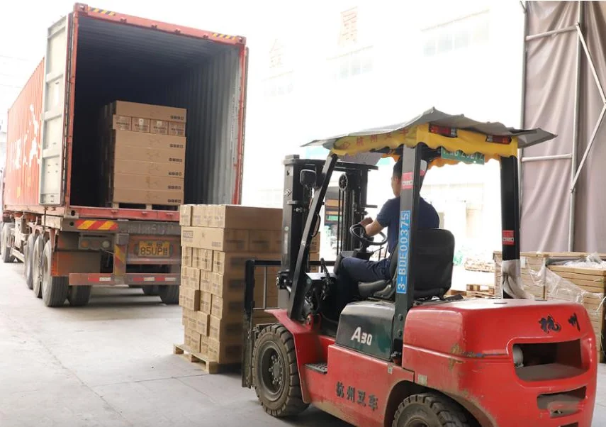 Forklift loading packed cartons beside a shipping container