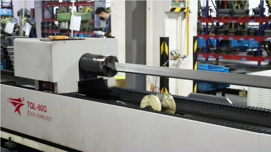 Tube cutting equipment processing a metal profile in the NATE workshop