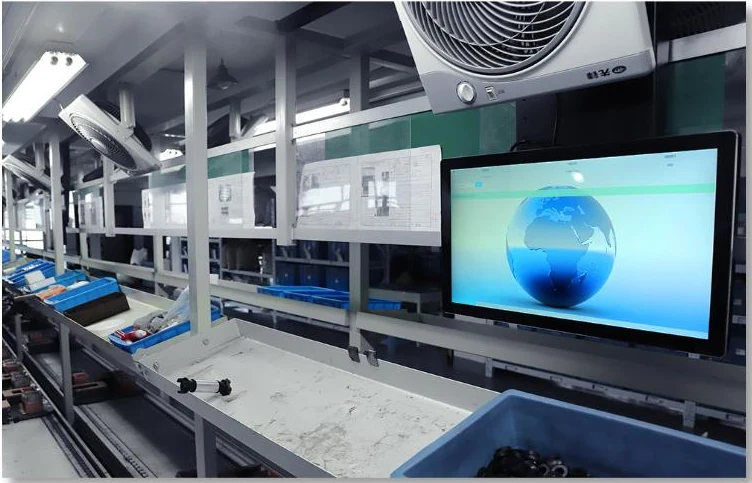 Digital production information screens beside a NATE factory workstation